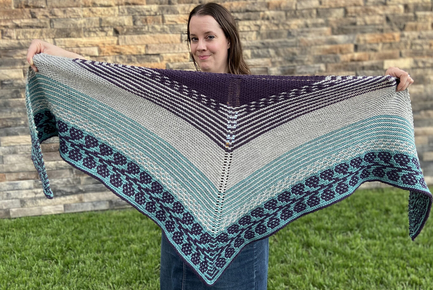 hand knit shawl in shades of blue, cream, and purple and featuring colorwork patterning and striping