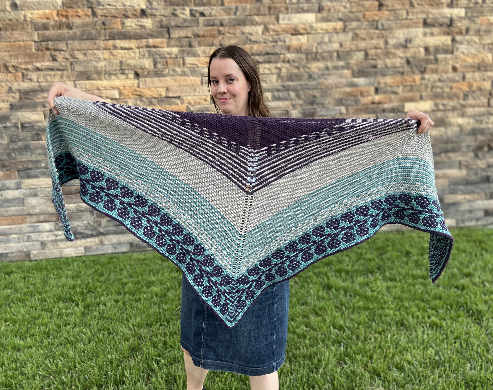 hand knit shawl in shades of blue, cream, and purple and featuring colorwork patterning and striping