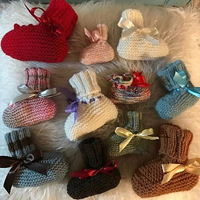 A bird's eye view of several handknit baby booties in various colors