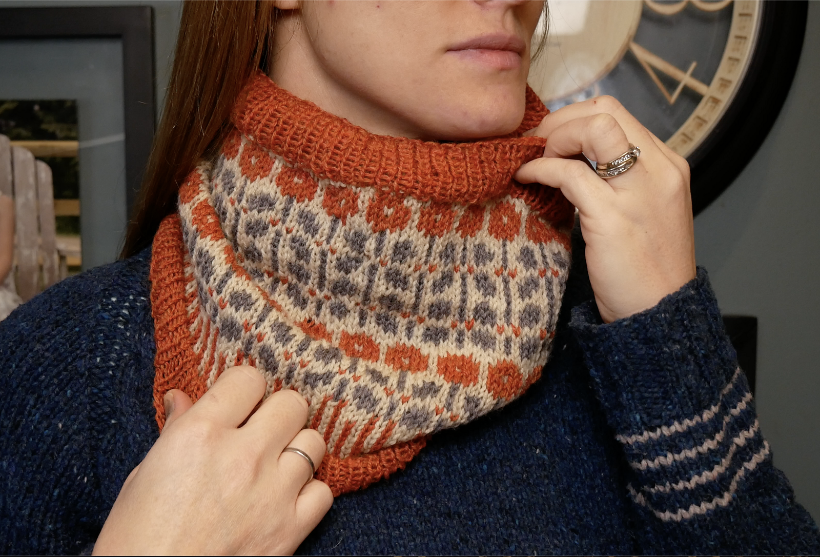 A knit colorwork cowl with orange flowers and green details