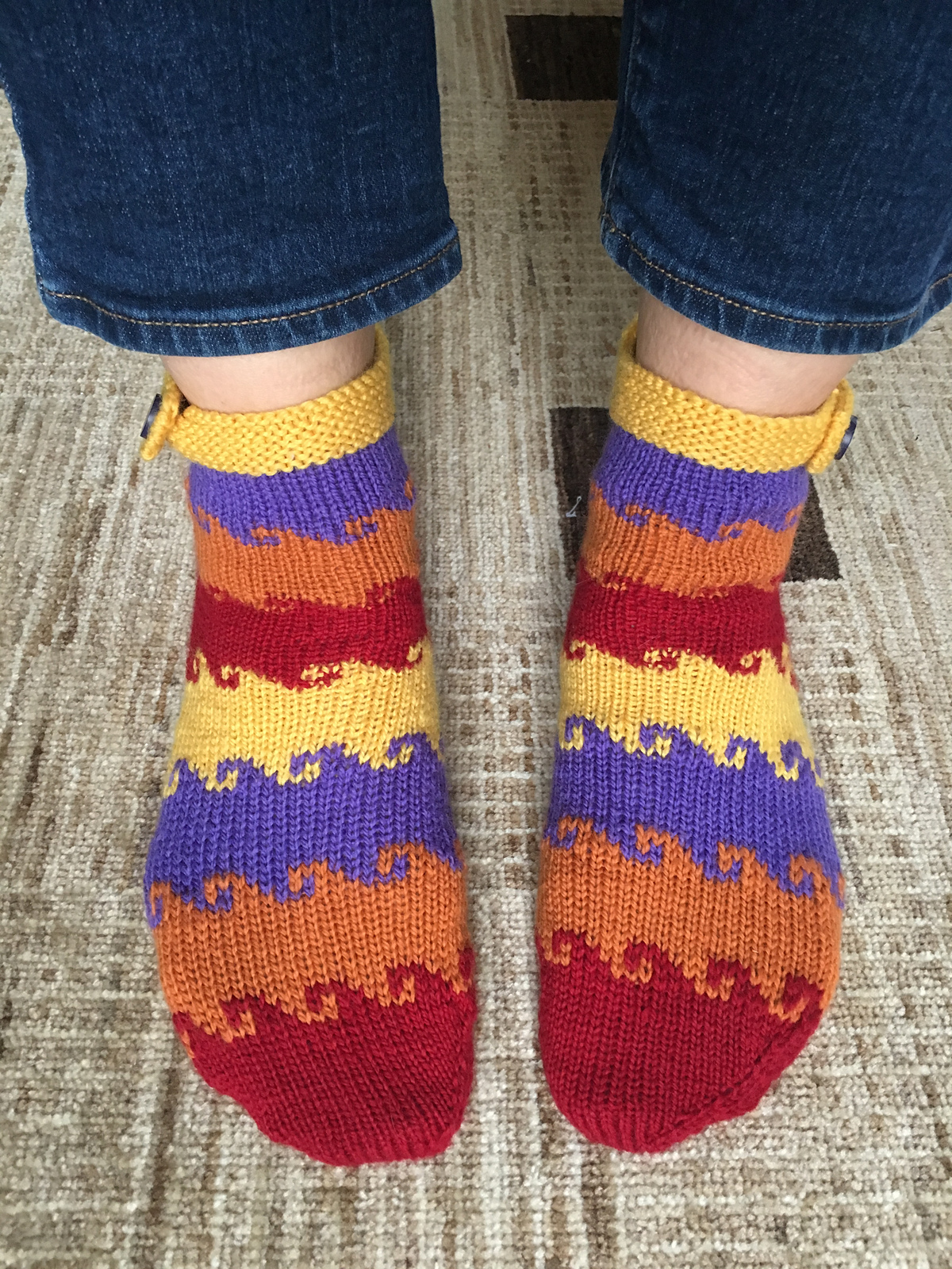 Hand knit socks featuring thick stripes of color and curling flourishes between each stripe