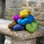 Harborside Aran in bright colors piled on a stone bench