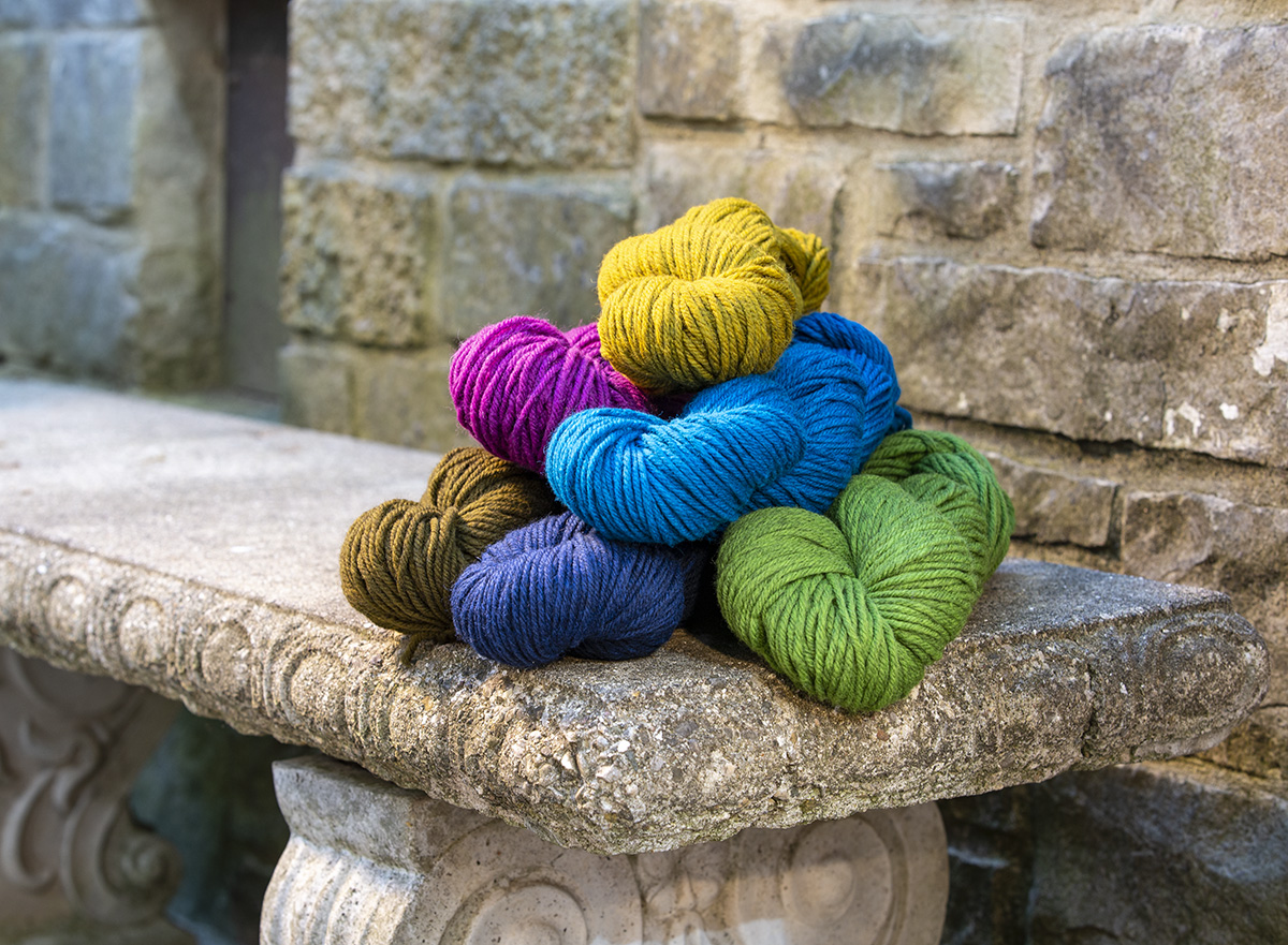 Harborside Aran in bright colors piled on a stone bench
