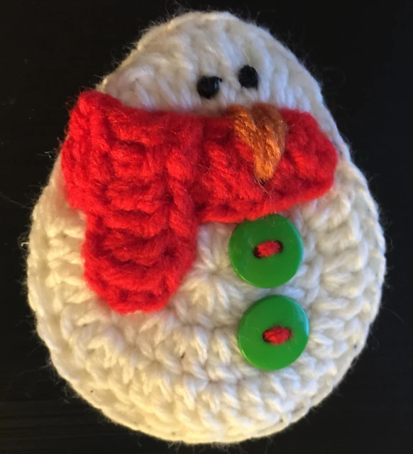 round crocheted snowman ornament with red scarf and green buttons