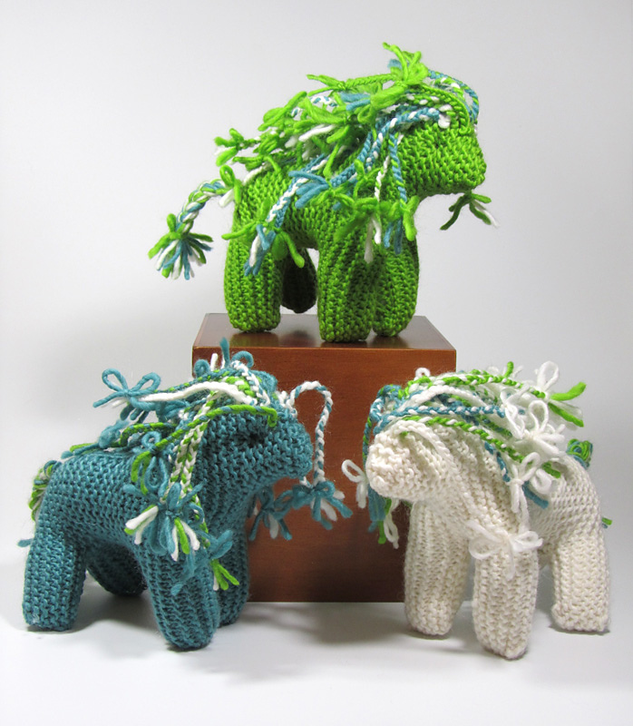 a selection of handknit ponies in green, blue and cream