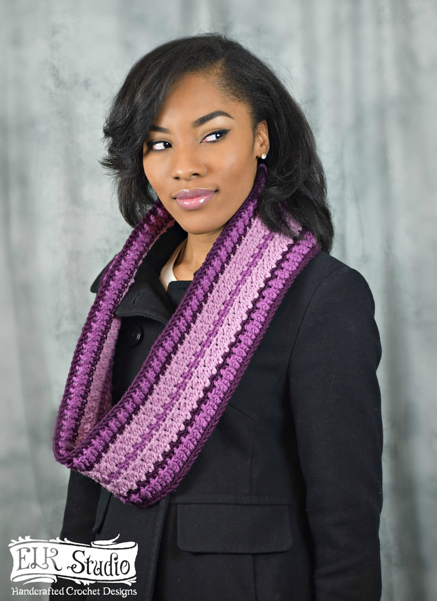 Black woman wearing a crocheted striped scarf in several shades of purple