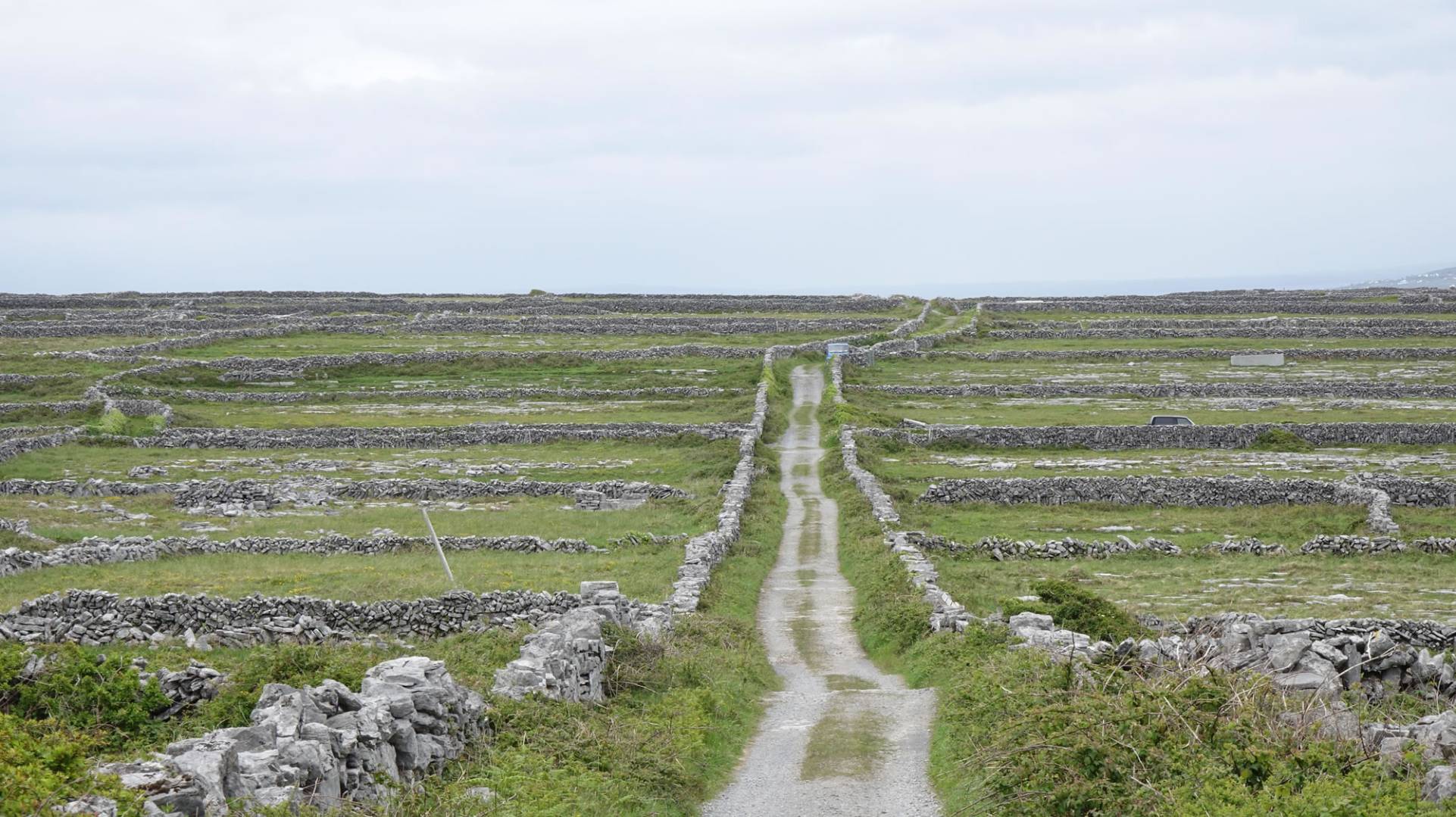 a green landscape bisected by a gray road known as the High Road in Inis Mor