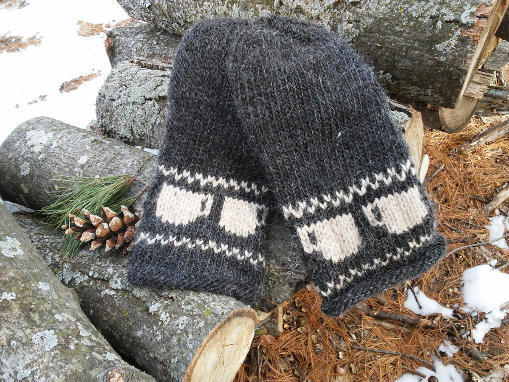 knit dark gray mittens with a simple colorwork design showing coffee mugs in a cream color on the cuff