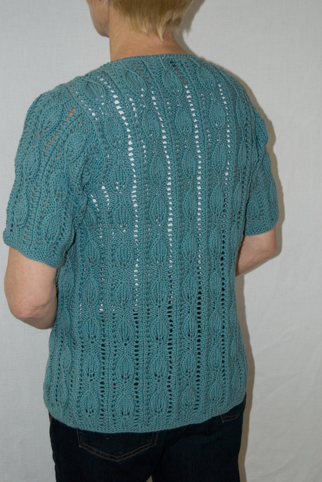 the back of a teal lace leaf short sleeve cardigan